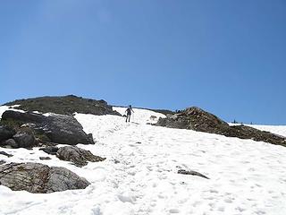 There's still some snow left on the trail as Kolleen heads up the slope into azure blue skies