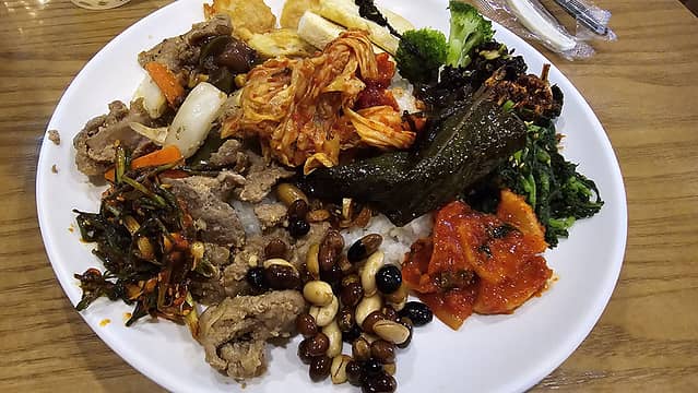 Korean breakfast (starting clockwise from noon, tofu, broccoli, seaweed, dried minnows, greens, kimchi, peanuts with fermented soy beans, ???, kimchi, meat, onion, ???.  And in the middle several other kimchi's over rice)
