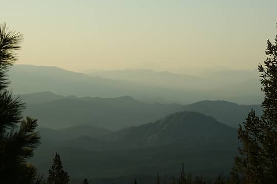 Overlapping ridges and mountains obscured by haze with Glacier Peak in the background.