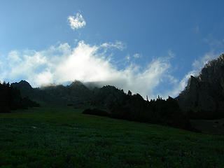 Clouds draping jagged peaks over the meadow.