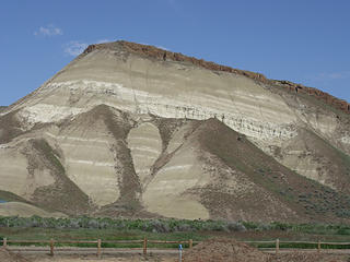 Carroll's Rim looms above the Painted Hills Unit, displaying layers of ash and clay capped with basalt.