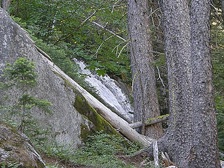 Waterfall view through trees on trail to Colchuck Lake.