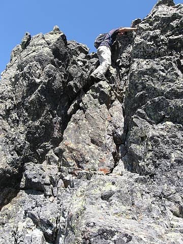 Nick drops through the little summit chimney, crux of the scramble.