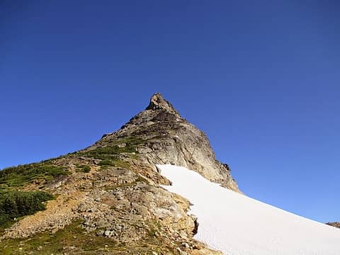 The route wraps around the left hand side at the dark shadow below the summit